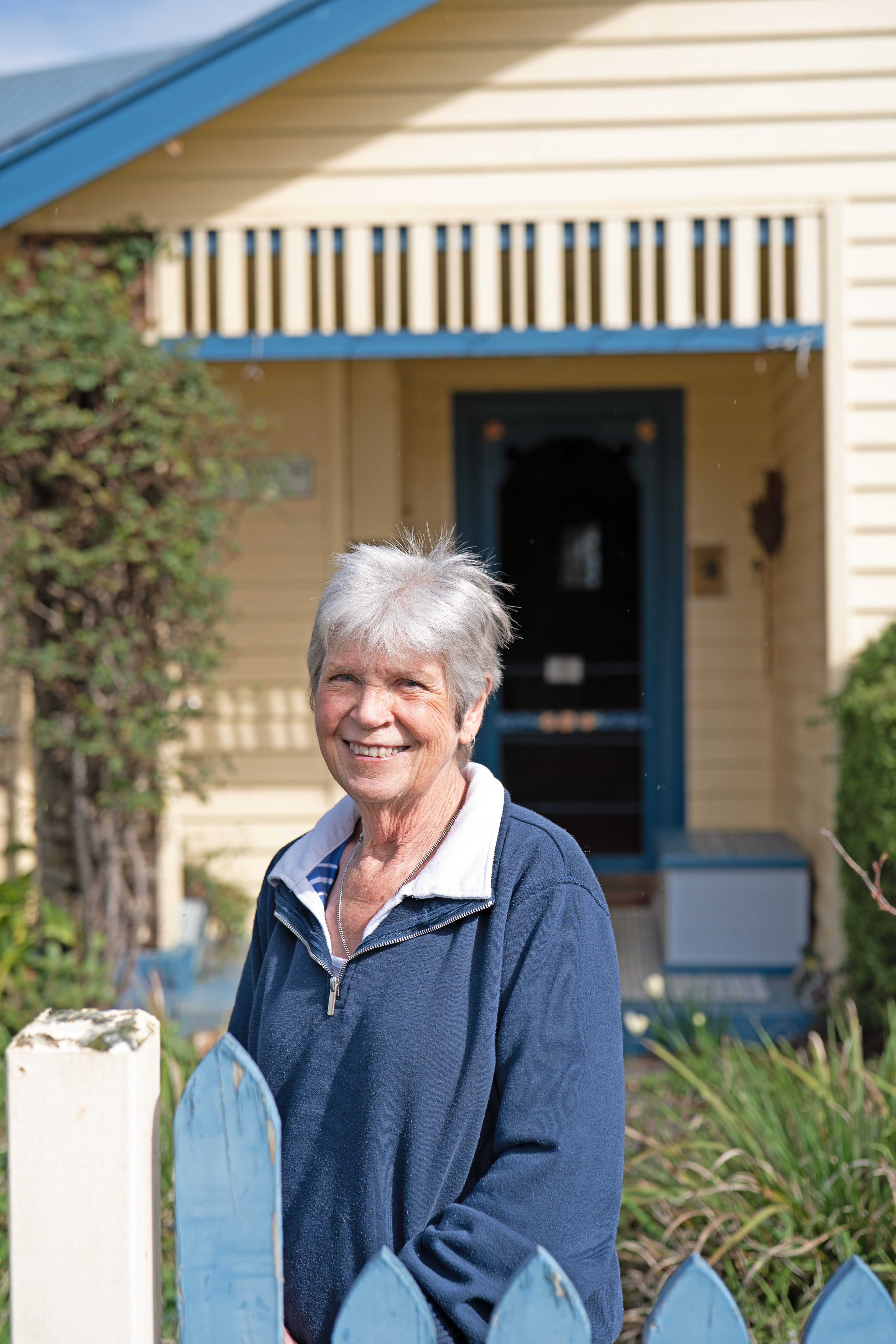 A woman standing outside her weatherboard house