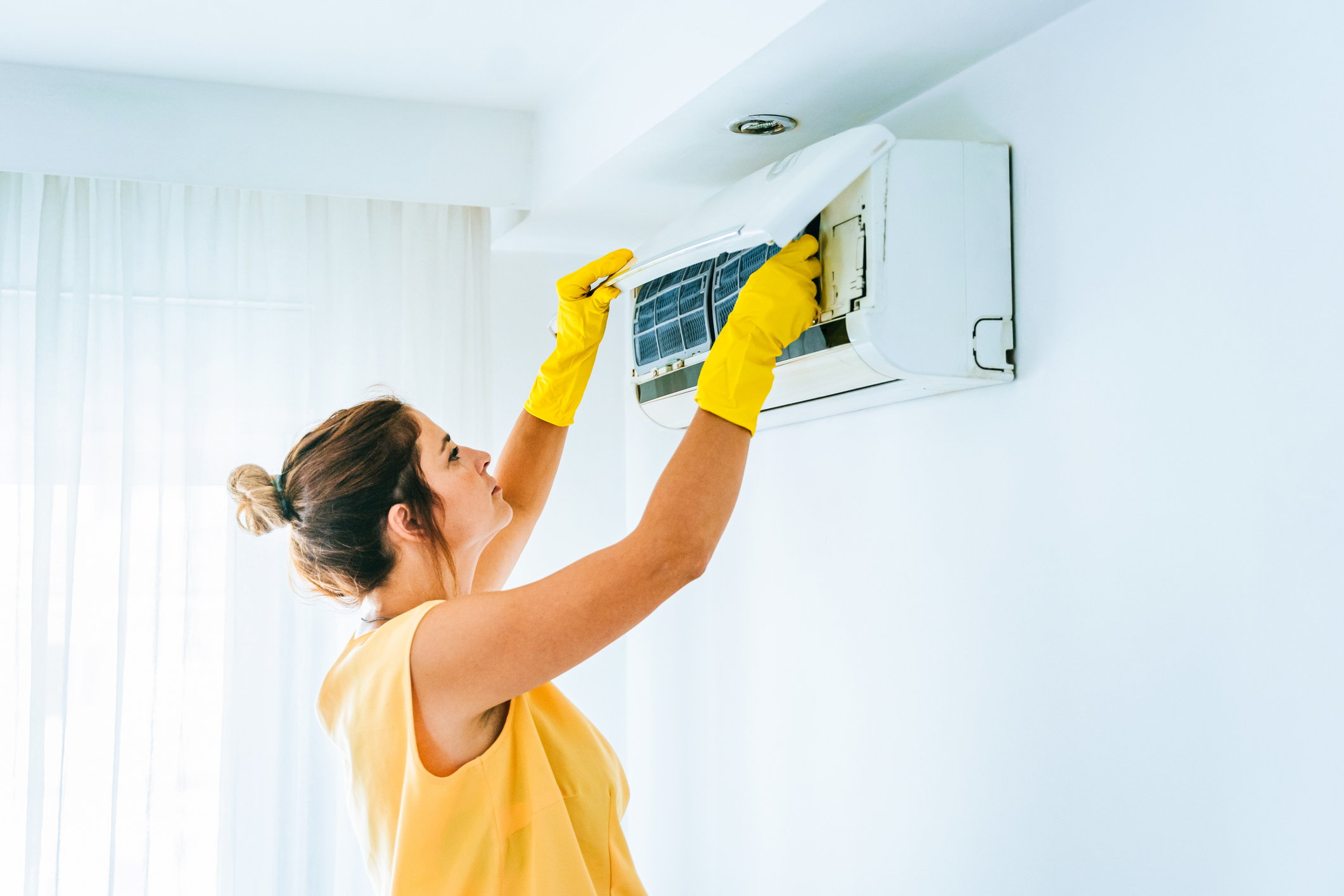 Cleaning air conditioning unit by removing the fan cover with yellow rubber gloves on