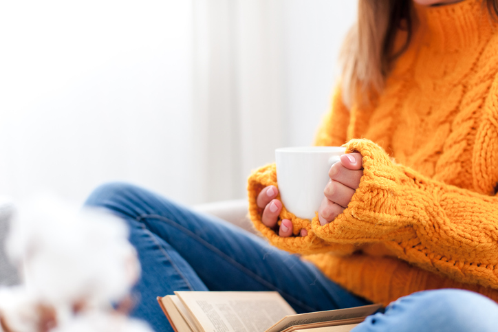 Woman in orange knit jumper holding a warm cup of tea
