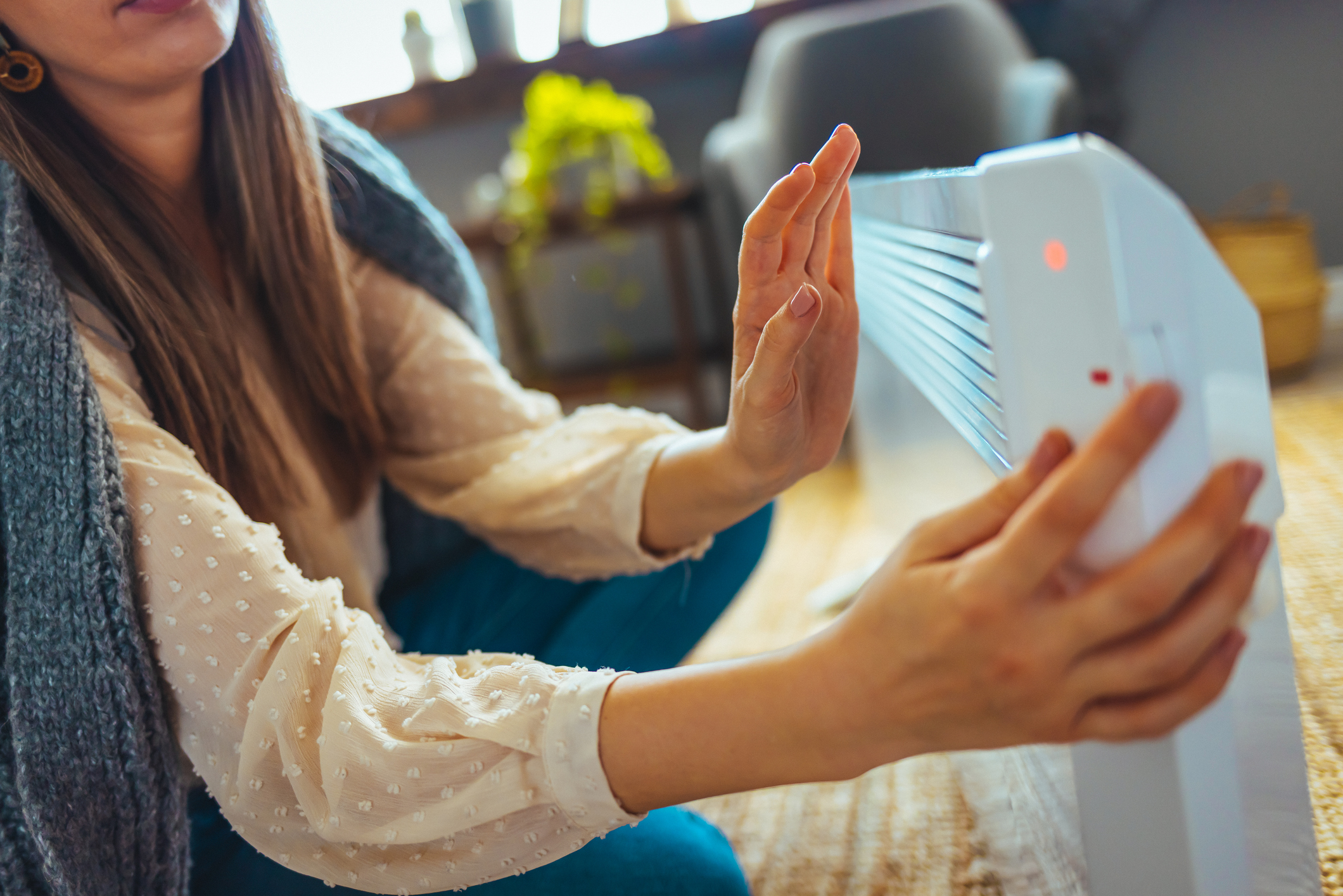 Woman holding hand next to radiant bar heater