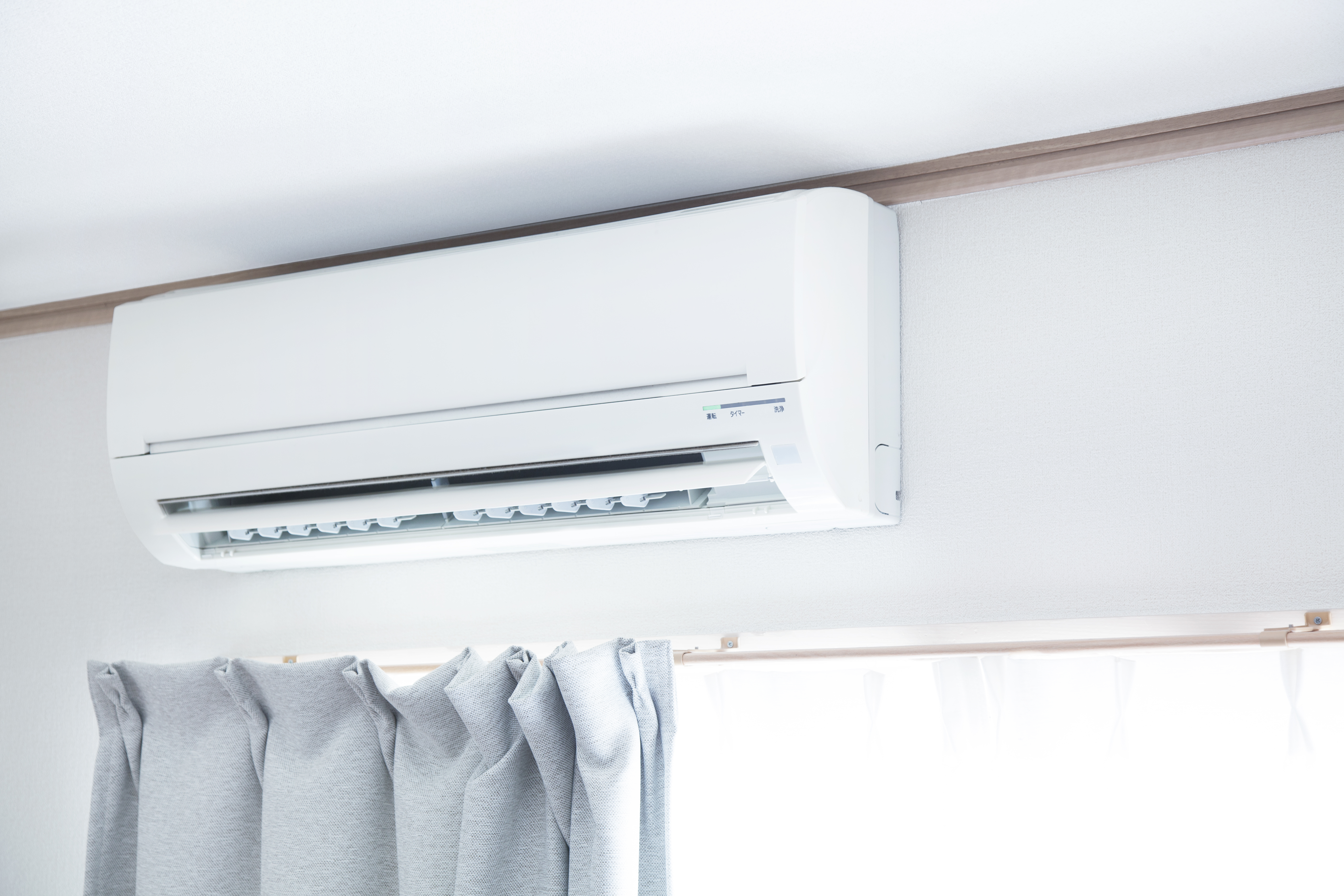 Heat Pump on wall above a window with grey curtains