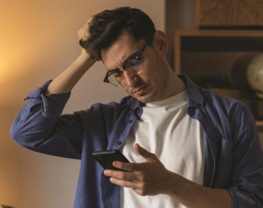 Man looking at his phone with a puzzled expression
